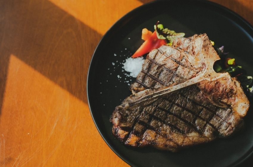 T-bone yang disajikan diatas piring dengan side dish yang menggugah selera